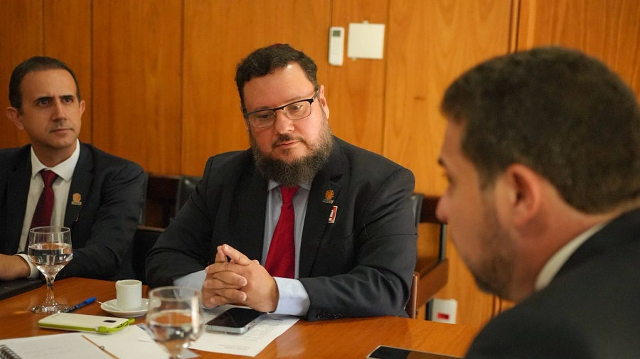 Leonardo Cunha de mãos entrelaçadas, olha para a mesa enquanto Boulos fala