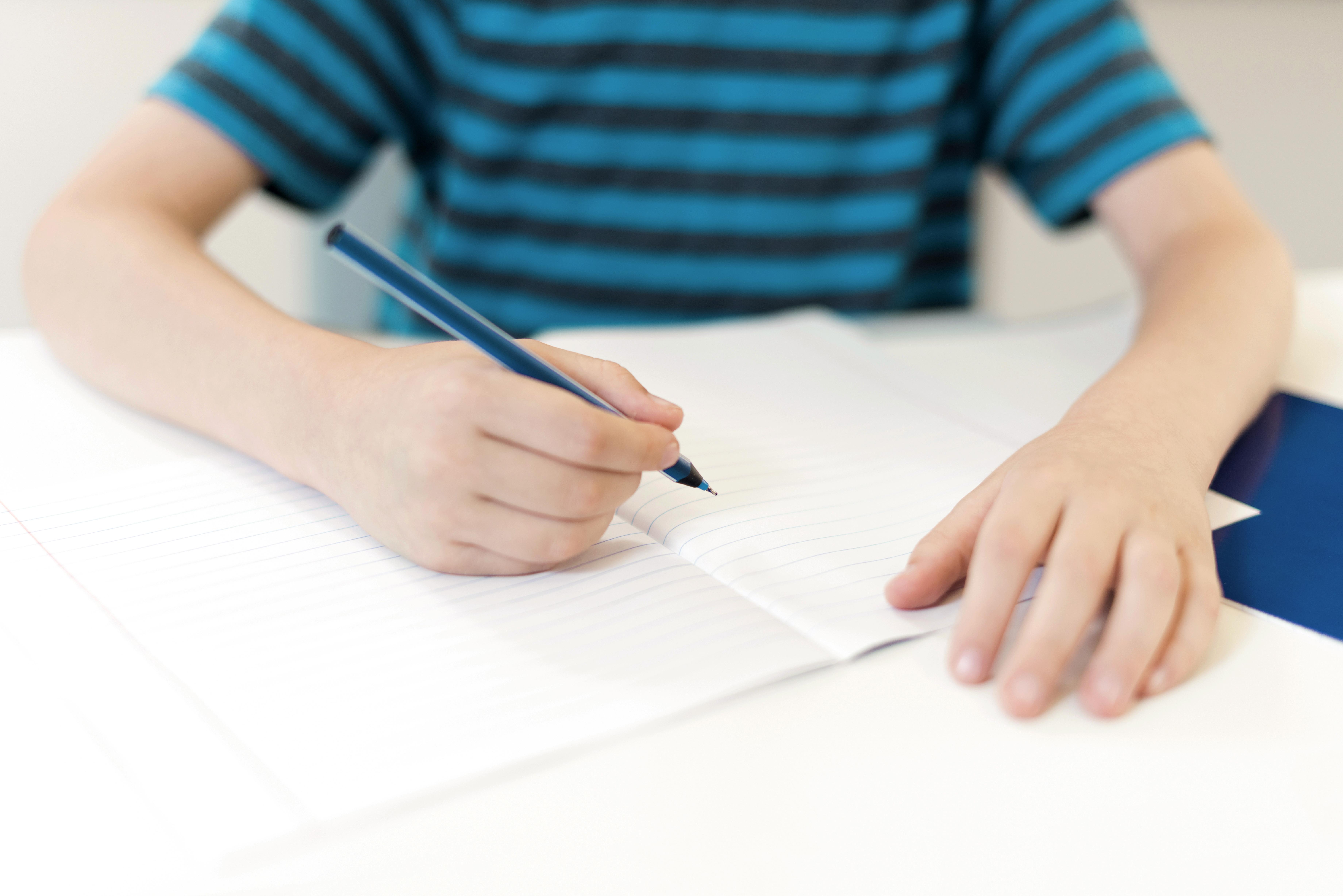 criança escrevendo em caderno em branco